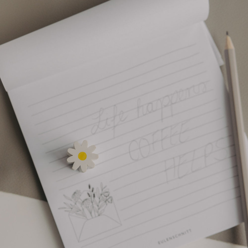 Radiergummi Daisy einzeln auf Notizblock neben Bleistift