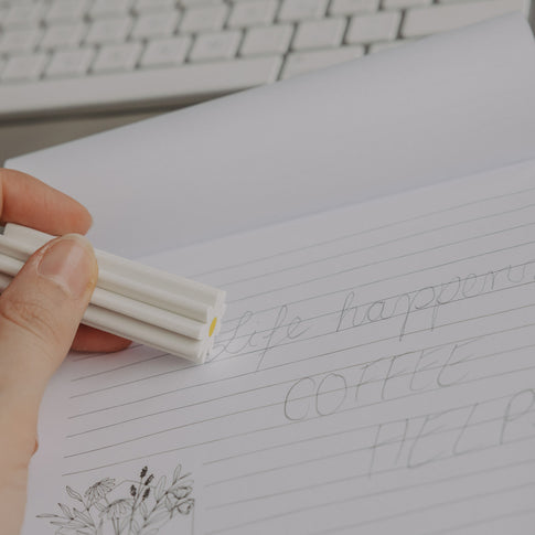 Hand hält Radiergummi Daisy und radiert auf linierten Notizblock