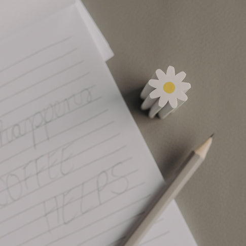 Radiergummi Daisy neben Notizblock und Bleistift auf Schreibtisch