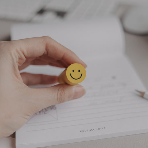 Radiergummi Smiley wird in der Hand gehalten vor Notizblock