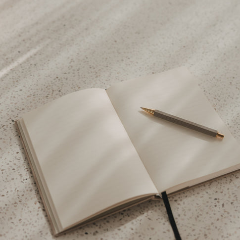 Offenes A5 Notizbuch mit linierten Seiten, schwarzem Leseband und Stift