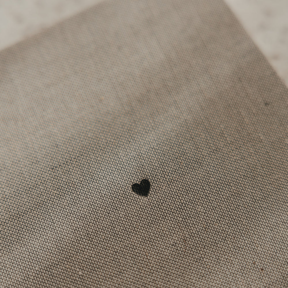 Detail des grau beigen Stoffeinbands vom karierten A5 Notizbuch mit kleinem schwarzem Herz