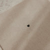 Detail des beigen Leineneinbands mit kleinem schwarzem Herz auf der Vorderseite des Gästebuchs
